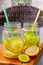 Two mason jar glasses of homemade lemonade with part of lemons