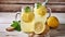 Two mason jar glasses of homemade refreshing lemonade with slices of organic ripe lemon, whole and halves, juicer, muddler,