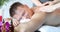 Two masseuses give relaxing massage to young man closeup