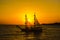 Two-masted sailing ship on the background of the setting sun.