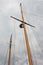 Two masts from a large sailboat against a stormy sky with clouds