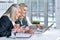 Two mature businesswomen sitting at table with laptop and working together