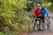 Two Mature Male Cyclists Riding Bikes Along Path