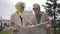 Two mature women in headscarves and sunglasses holding the map and talking. Senior ladies travelling after retirement