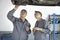 Two Mechanics Looking at Underside of a Car, Discussing