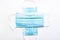 Two medical blue disposable face shields one on top of the other crosswise on a white background. A surgical dressing