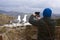 Two Mediterranean gulls Larus michahellis stand on the stone wall of the old fortress.  A man photographs birds on a smartphone.