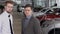 Two men against background of car salon with new models of transport. slow motion.