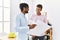 Two men architect workers smiling confident holding blueprint standing at architecture studio