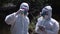 Two men in biohazard suits sampling water