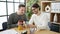 Two men business partners drinking coffee using smartphones at office