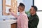 Two men business workers writing on cork board at office