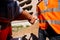 Two men dressed in shirts and orange work vests shake hands against the background of a multistorey building