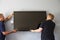 Two Men Fitting Flat Screen Television To Wall