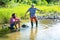 Two men friends fishing. Flyfishing angler makes cast, standing in river water. Old and young fisherman.