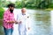 Two men friends fishing. Flyfishing angler makes cast, standing in river water. Old and young fisherman.