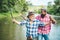 Two men friends fishing. Flyfishing angler makes cast, standing in river water. Old and young fisherman. Happy excited