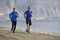 Two men friends running together on beach sand coast mountain bachground in healthy lifestyle concept