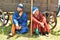 Two men in historical costumes from the time of the Mongol Empire sit in the shade near the cart