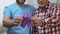 Two men holding violet ribbon, volunteer supporting old man, Alzheimers disease