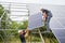 Two men installing solar panel system outdoors.