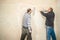 Two men with large spatulas plaster the wall in an empty room. Masters in dirty clothes perform work on the plaster of the