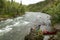 Two men launch canoes beside Alaskan river rapids