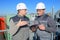 two men looking at tablet stood overlooking industrial factory