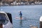 Two men on paddle boards rowing along the Huntington Harbour with boats and yachts docked, luxury homes and lush green palm trees