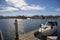 Two men on paddle boards rowing along the Huntington Harbour with boats and yachts docked, luxury homes and lush green palm trees