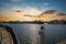 Two men on paddle boards rowing along the Huntington Harbour with boats and yachts docked, luxury homes and lush green palm trees