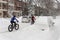 Two men are riding bikes during snowstorm