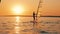 Two men are sailing on windsurf boards at sundown