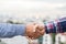 Two men shaking hands to dealing success agreement business. Business people wearing scott shirt on city view background