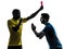 Two men soccer player and referee showing red card silhouette