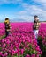 Two men standing tall amidst a sea of vibrant purple tulips in a stunning field in the Netherlands, with windmill