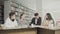 Two men and two women college students laughing while preparing for exams while sitting at table at university library