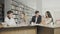 Two men and two women college students laughing while preparing for exams while sitting at table at university library