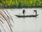 Two men wearing traditional Vietnamese clothing rowing a boat