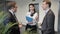 Two men and woman are talking, laughing while standing in lobby of company.