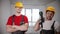 Two men workers standing in draft apartment holding instruments