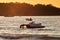 Two mens at sunset pull hydrocycle out of the water. Summer vacation. Water bike loaded onto a trailer