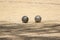 Two metal balls from the game of petanque approaching the bowling ball on a sandy ground of a petanque court on a sunny day with