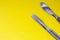 Two metal chrome surgical scalpel are on a yellow background with space for text and headings. Photo illustration in medical surge