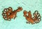 Two metal decorative fighting game roosters mounted on turquoise stucco wall swith screws