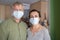 Two middle aged person with protective mask at home due to coronavirus quarantine