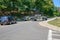 Two military Jeep vehicles are seen blocking a small tree lined country road. A Mini van is being stopped from proceeding onto the