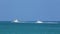 Two military speedboats quickly floats away into distance on blue surface of sea leaving behind white foam traces