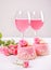 Two mini cakes, glasses with pink grape wine and rose flowers on a white table. Romantic dinner concept