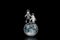 Two miniature astronauts floating in space against the Moon`s face. Close-up shot, isolated on black